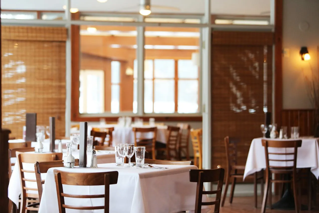 restaurant with many chairs and tables with tablecloths and glassware